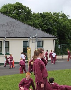 Pupils in the yard at breaktime, with the school building behind them