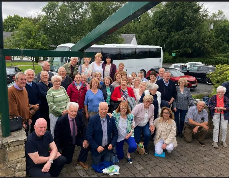 A group of travellers gathered outside the Fr Peyton Centre with the coach behind them